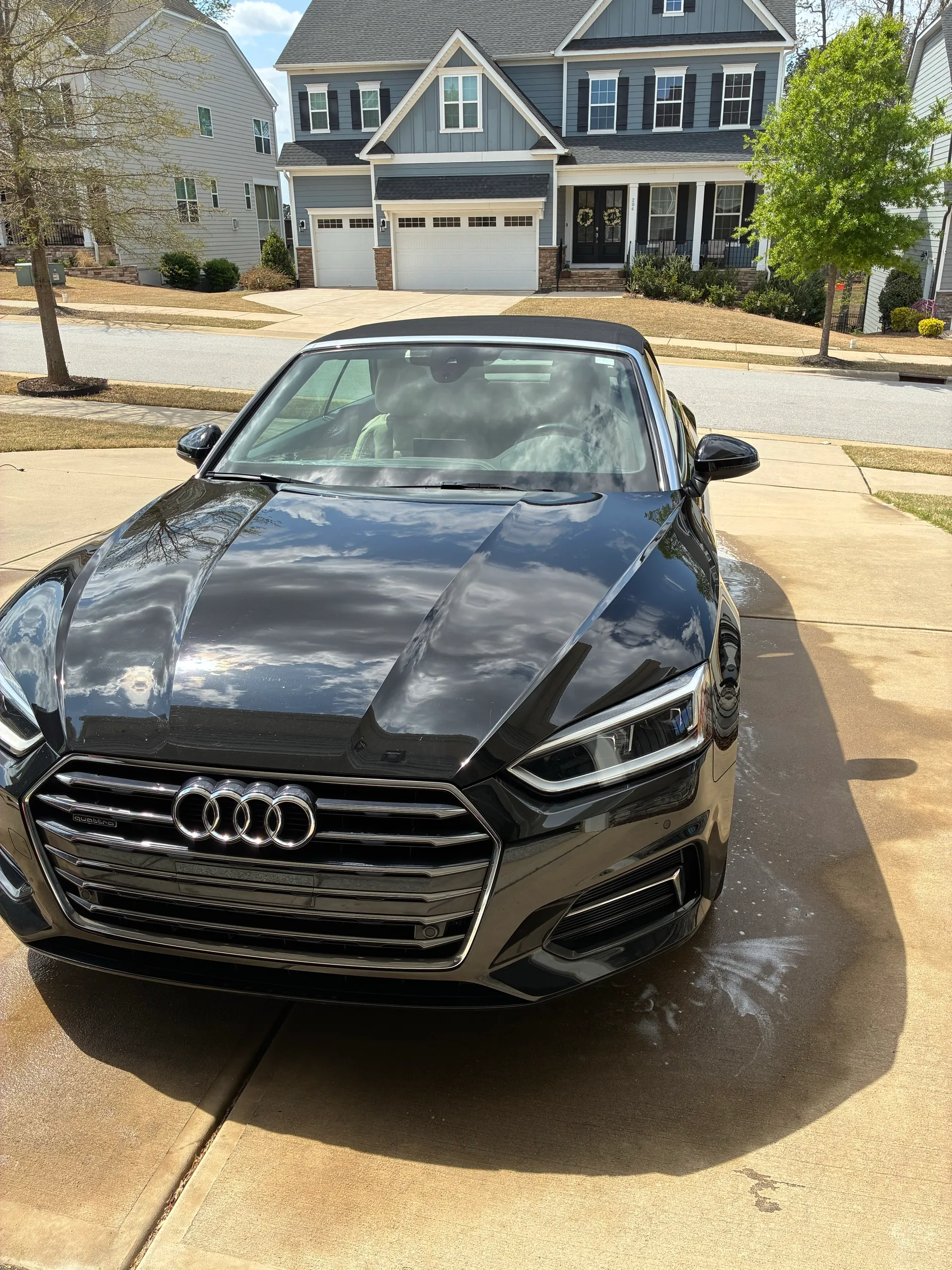 Straight-on front view of a black Audi A5 after a full exterior detail, showing polished grille and headlights