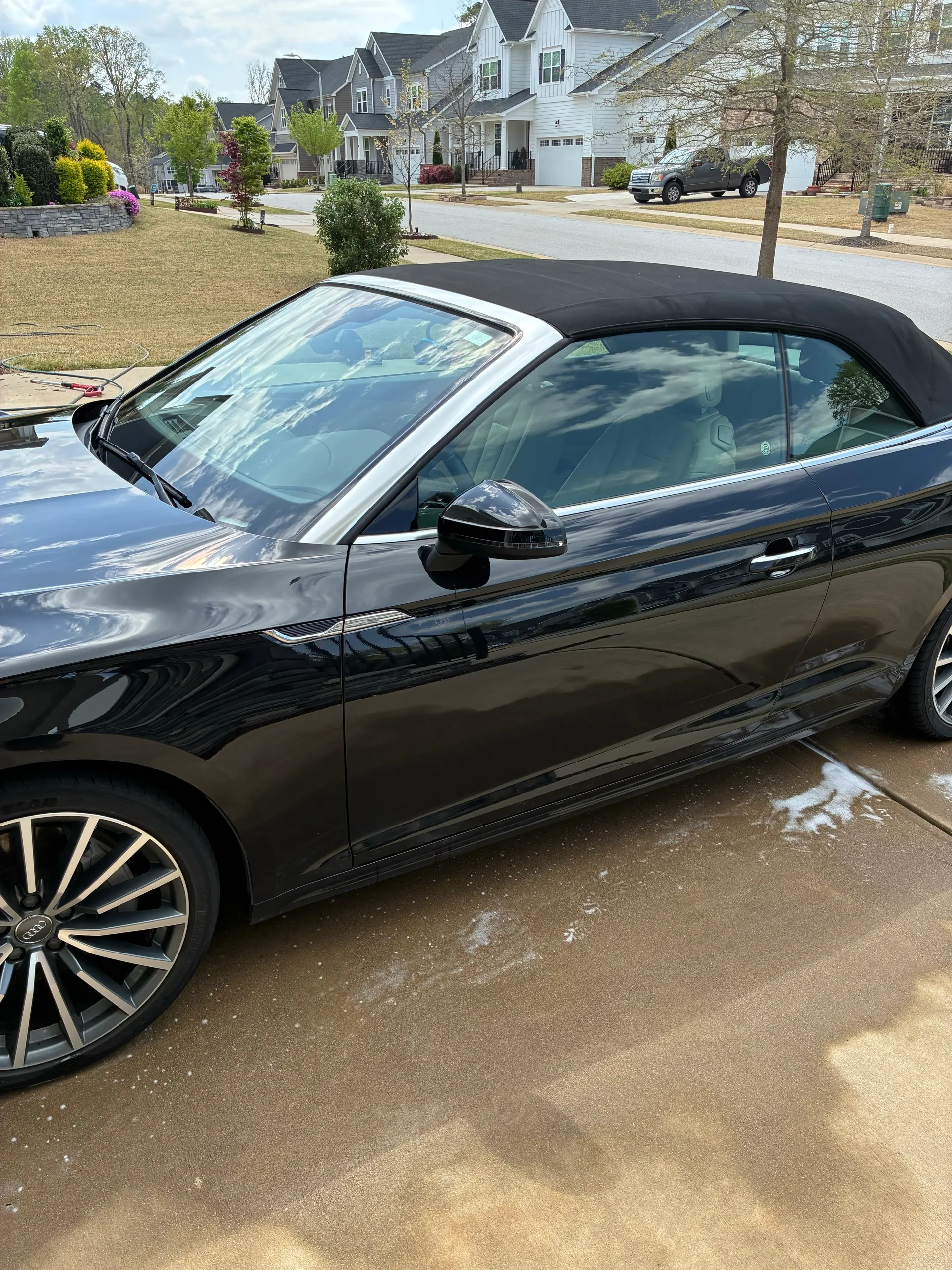 Side profile of a black Audi A5 Cabriolet after a full exterior wash, parked in a residential driveway