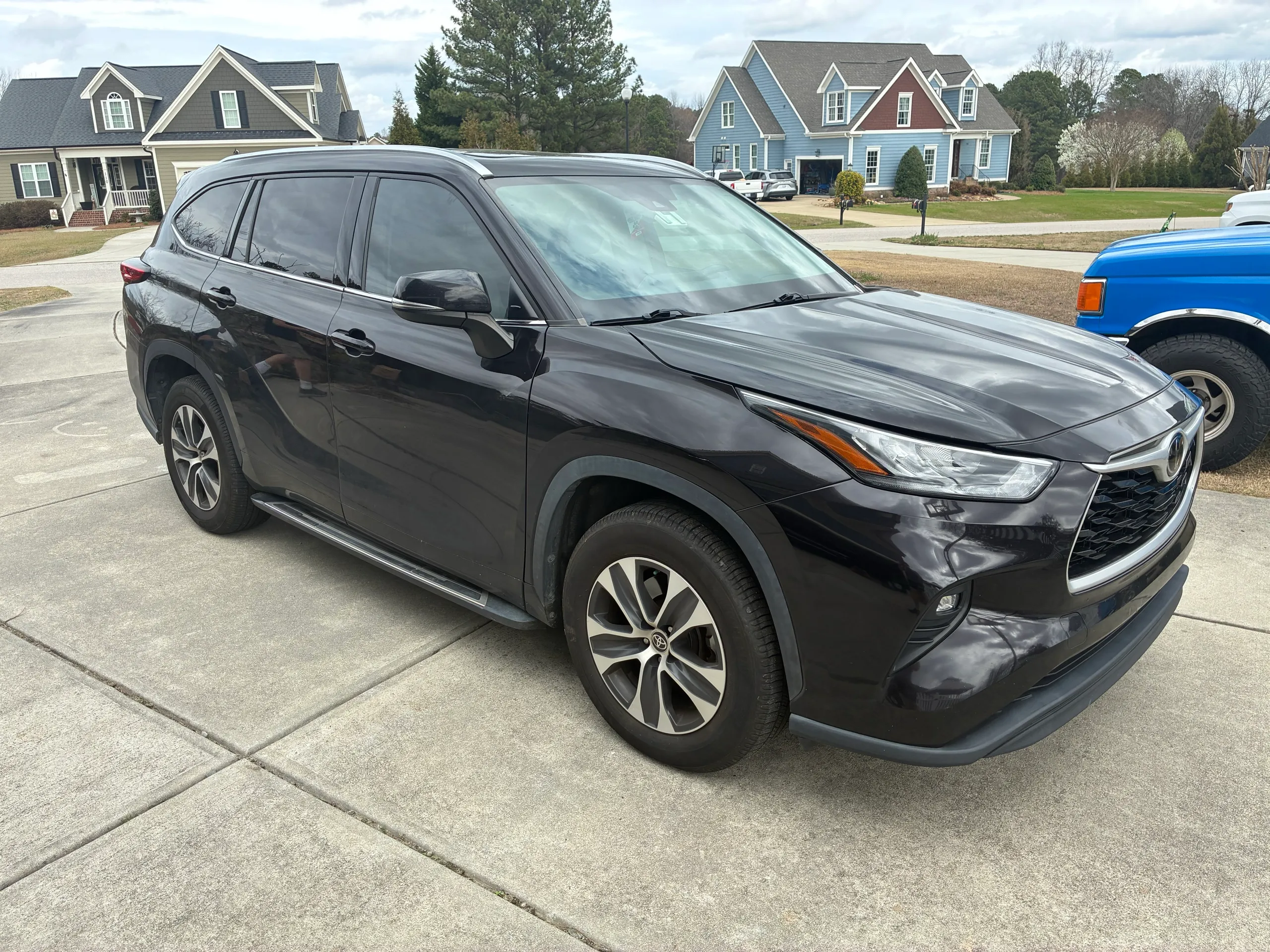 Black Toyota Highlander parked in a residential driveway after a full exterior detail