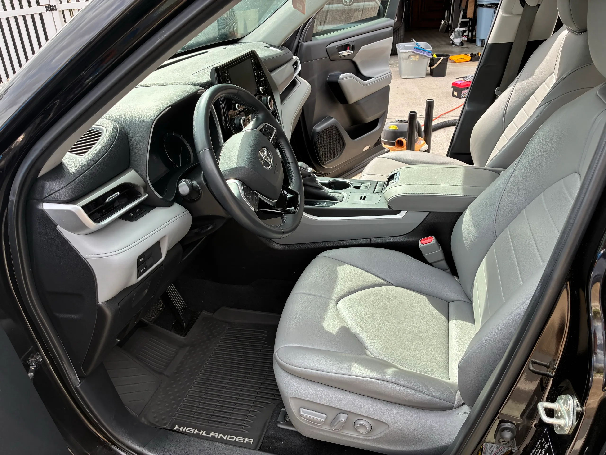 Front interior of a Toyota Highlander showing the driver seat, steering wheel, and dashboard after detailing